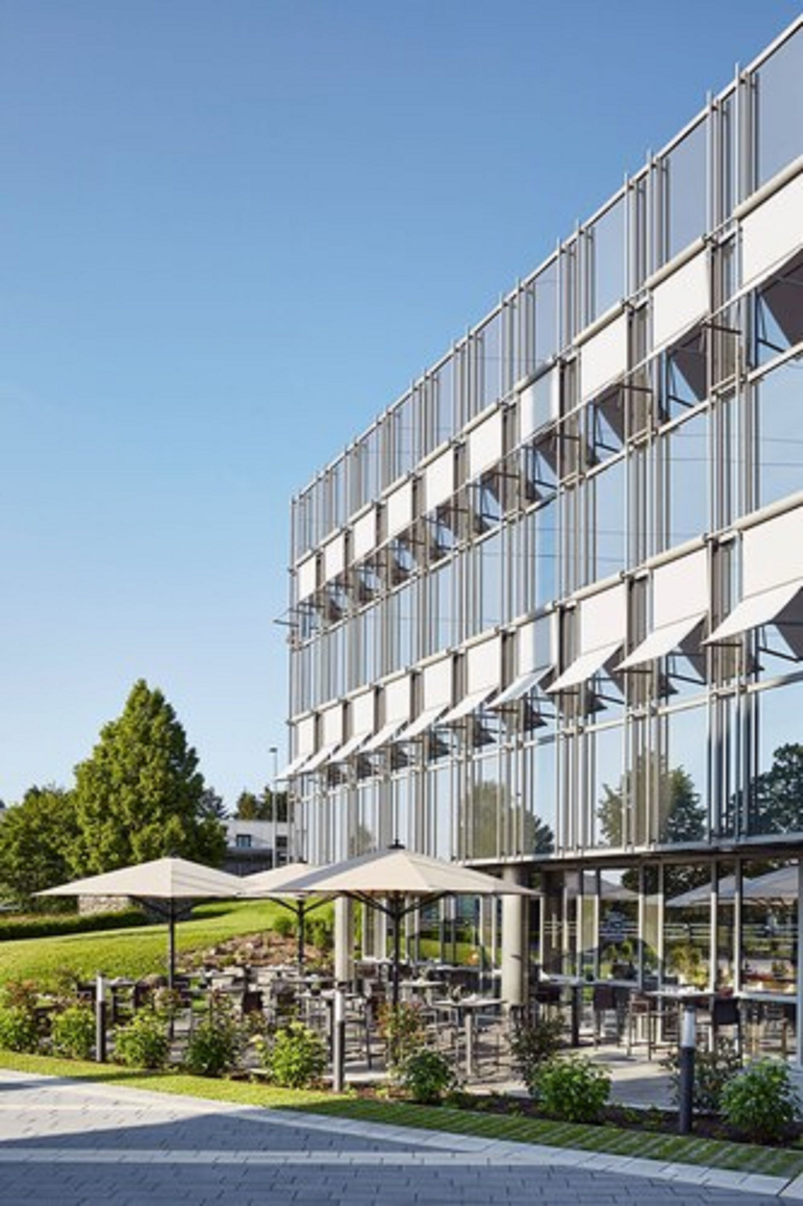 Un edificio moderno con fachada de vidrio y zona de estar al aire libre.