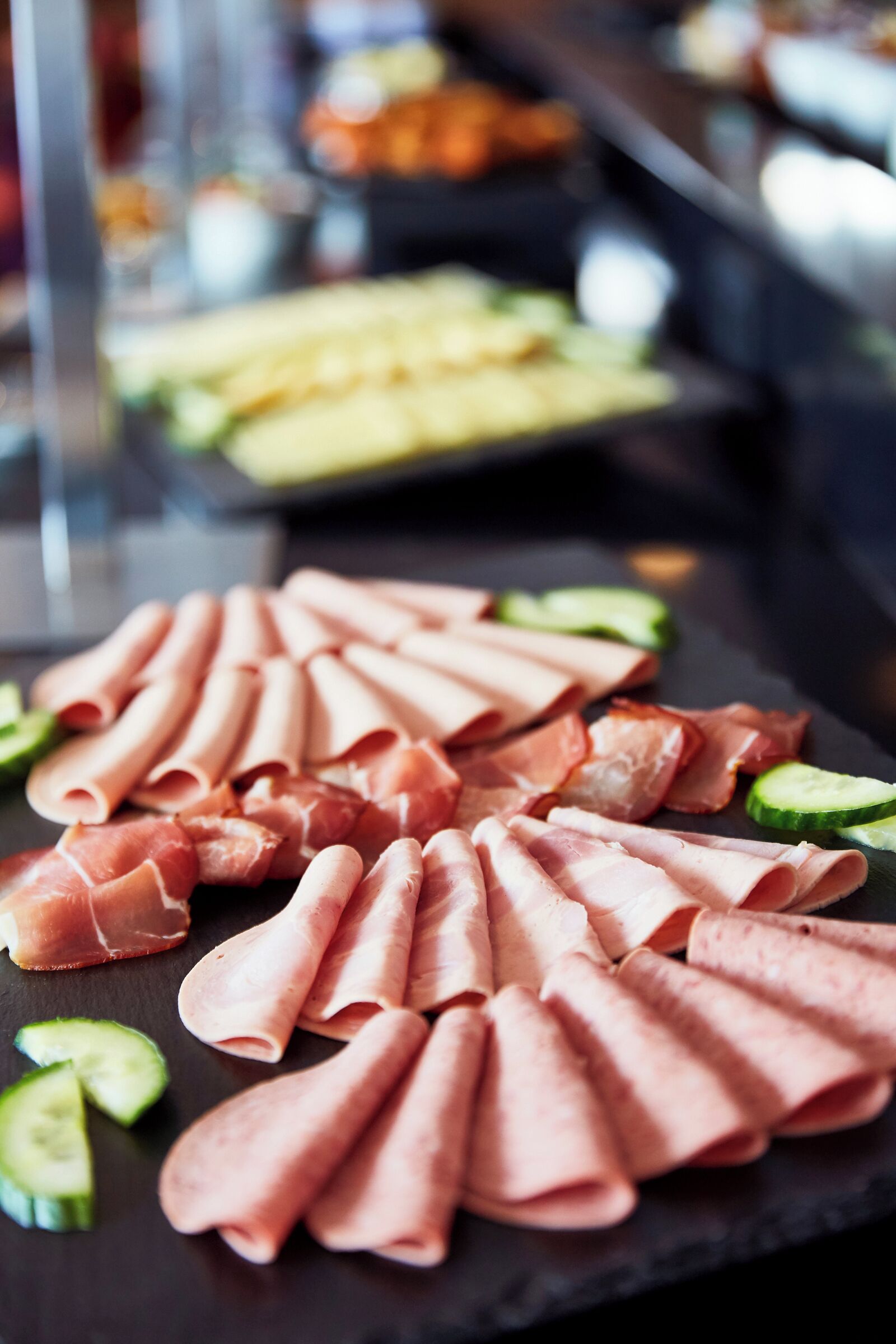 A charcuterie board with sliced meats and cucumber slices.