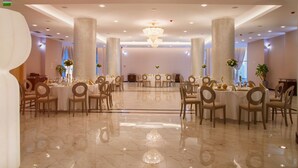 A spacious banquet hall with marble floors, large columns, and elegant chandeliers. -  Univers (T)  (Cluj-Napoca)