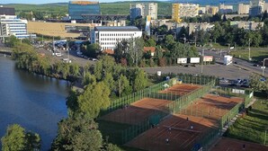 An aerial view of a tennis court complex with multiple courts, surrounded by trees and buildings. -  Univers (T)  (Cluj-Napoca)