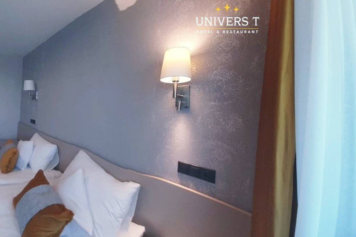 A hotel room with a large bed, a desk, a chair, a TV, and a mirror.