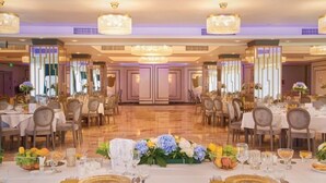 A banquet hall with round tables, chandeliers, and floral centerpieces. -  Univers (T)  (Cluj-Napoca)