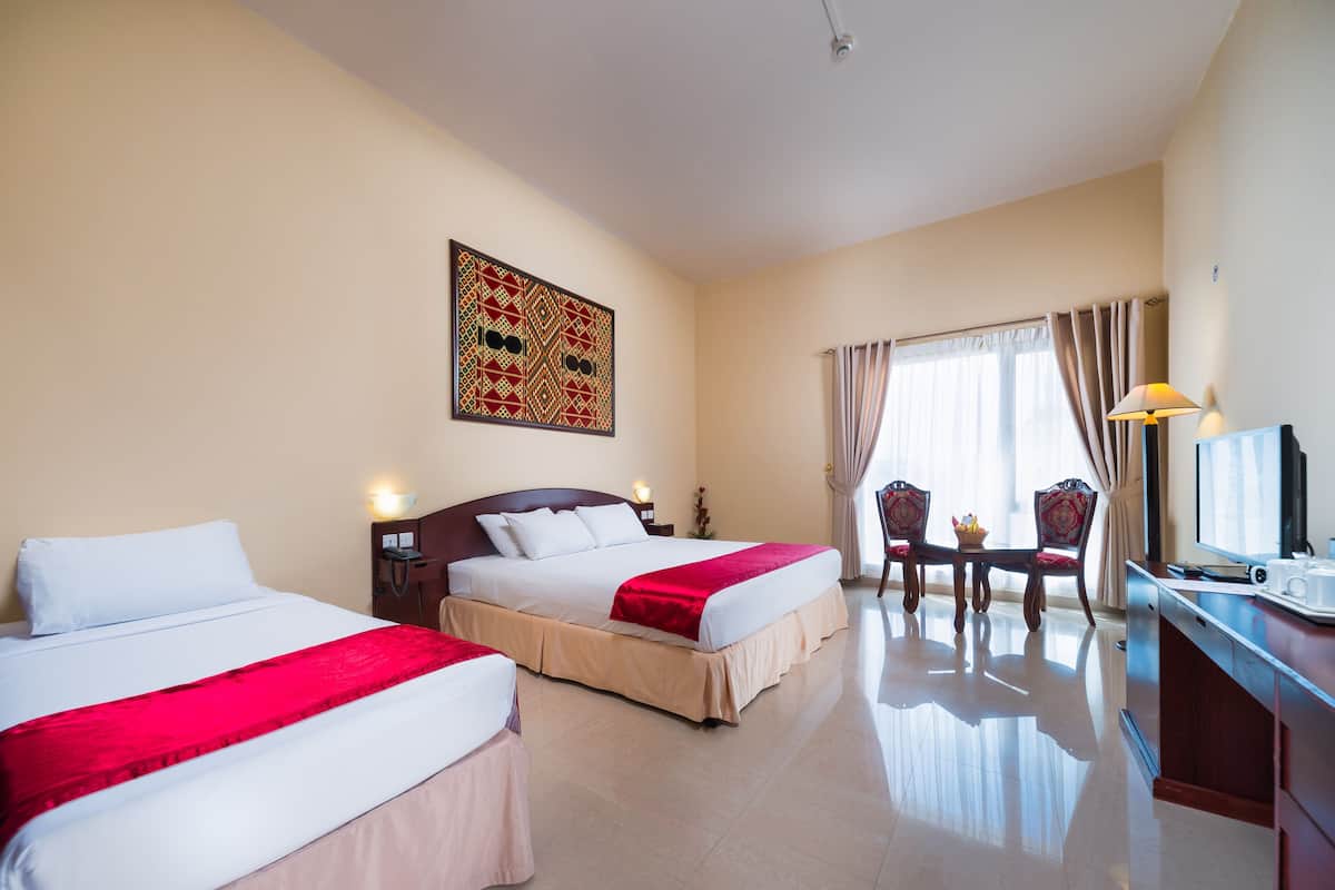 Habitación de hotel con dos camas, un escritorio con computadora, una silla y una ventana con cortinas.