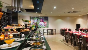 A buffet with various food items and a large poster on the wall. - Al Wadi Hotel Sohar (Sohar)