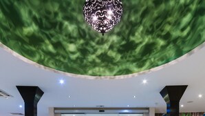 A spacious lobby with a modern design, featuring a large chandelier, a geometric floor pattern, and a view into the hotel rooms through a glass door. - Al Wadi Hotel Sohar (Sohar)