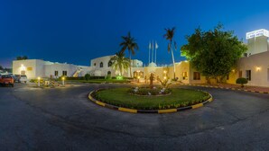 A hotel entrance with a landscaped garden, palm trees, and a sign for Al Wadi Hotel. - Al Wadi Hotel Sohar (Sohar)