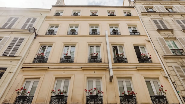 A multi-story building with white-framed windows, black wrought iron balconies with red flowers, and a visible sign that reads "Opéra". - Prince Albert Opera (Paris)