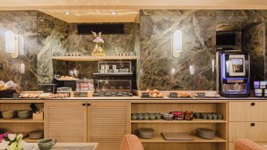 A modern breakfast bar with marble walls, a coffee machine, and various food items. - Prince Albert Opera (Paris)