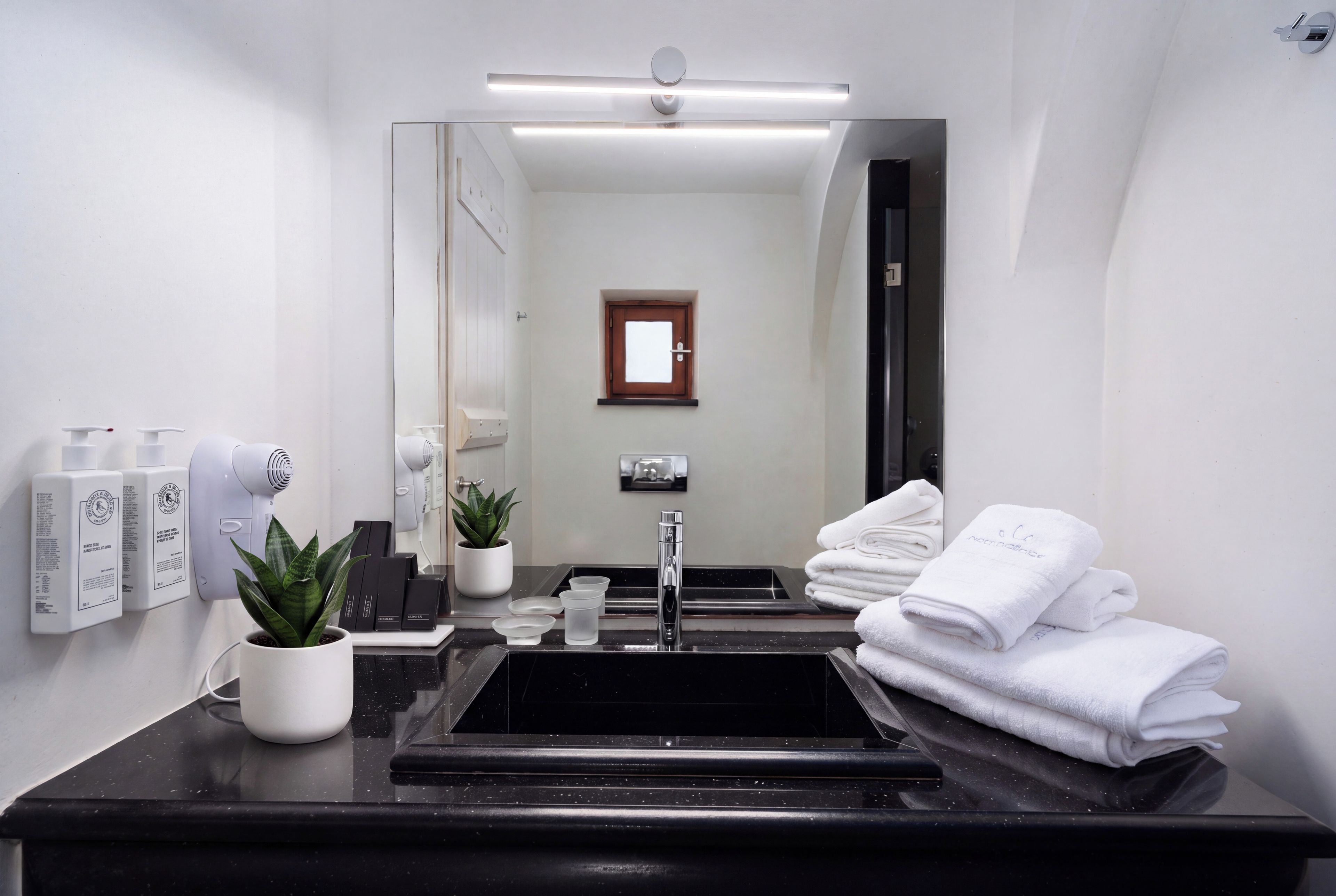 A modern bathroom with a black sink, white fixtures, and a large mirror.