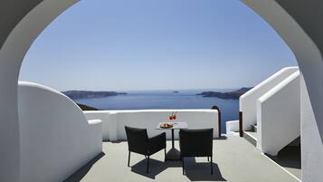 Balcón con paredes blancas, una mesa y sillas con vista al mar.