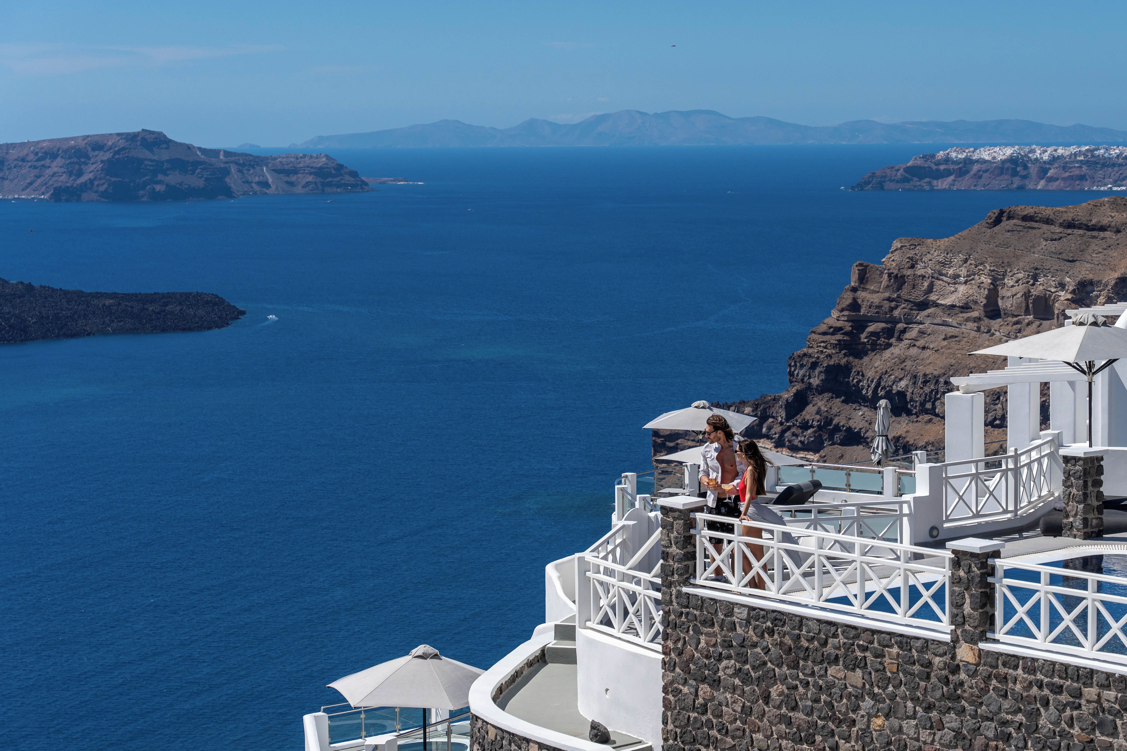 Un hotel frente al mar con balcón y vistas al océano, con montañas al fondo.
