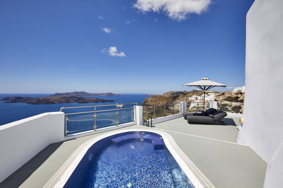 A rooftop pool with a clear view of the sea and rocky landscape.