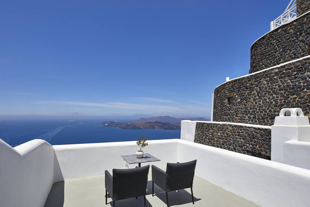 A terrace with a table and chairs overlooking the sea.