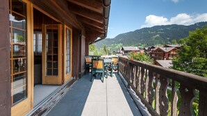 A wooden balcony with a view of a mountain and a village. - Alpe Fleurie (Ollon)