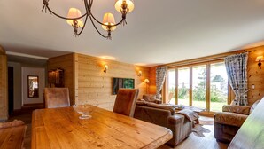 A wooden interior with a large dining table, leather seating, and a chandelier. - Alpe Fleurie (Ollon)