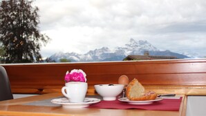 A table with a cup, bowl, and bread on a wooden bench with a mountain view in the background. - Alpe Fleurie (Ollon)