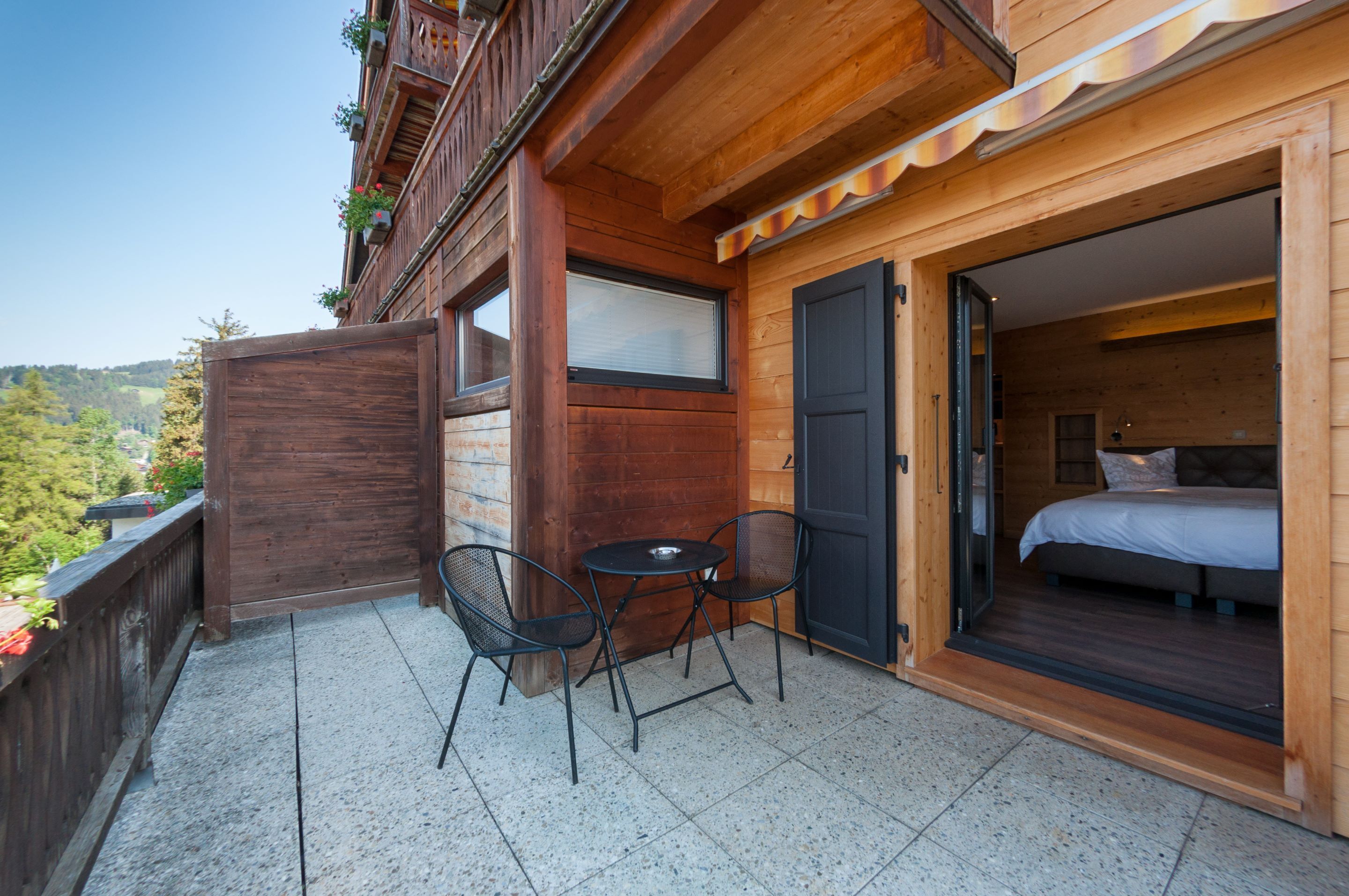 Una cabaña de madera con balcón, una cama y una pequeña mesa con sillas.