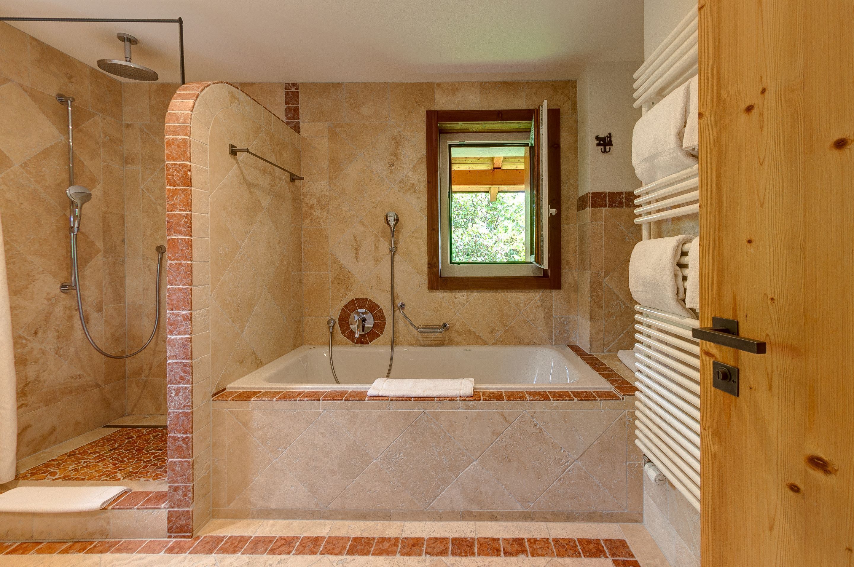 Ein Badezimmer mit Dusche, Badewanne und Fenster.