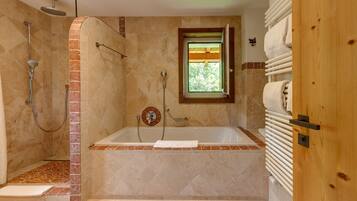 Ein Badezimmer mit Dusche, Badewanne und Fenster.