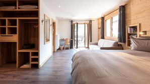 A bedroom with a large bed, wooden wardrobe, and a view of the outdoors. - Alpe Fleurie (Ollon)