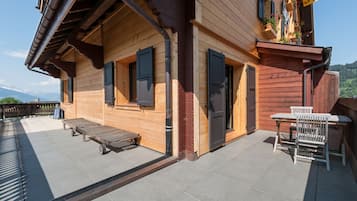 A wooden building with a balcony, a table with chairs, and a bench.