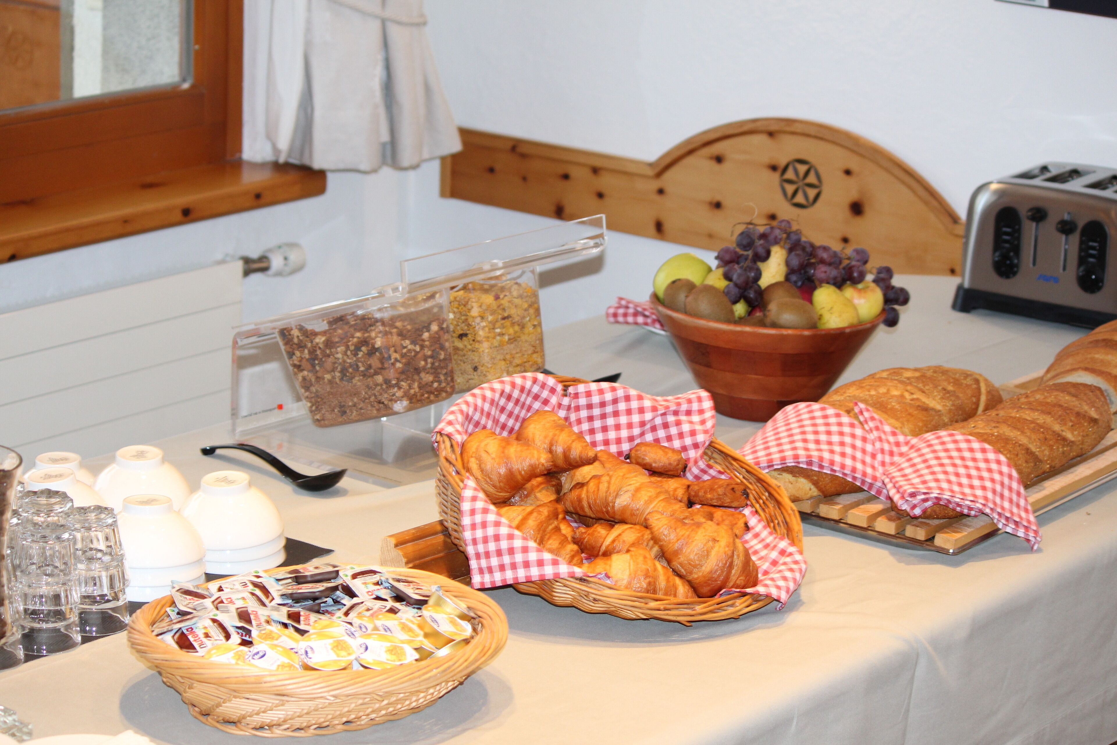 En morgenmadsbuffet med brød, kager og en skål med frugt.