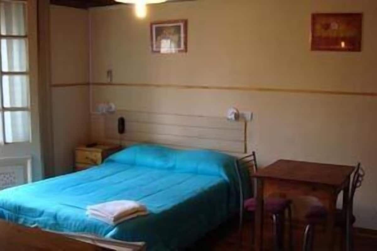 A bedroom with a bed, a small table, and a chair.