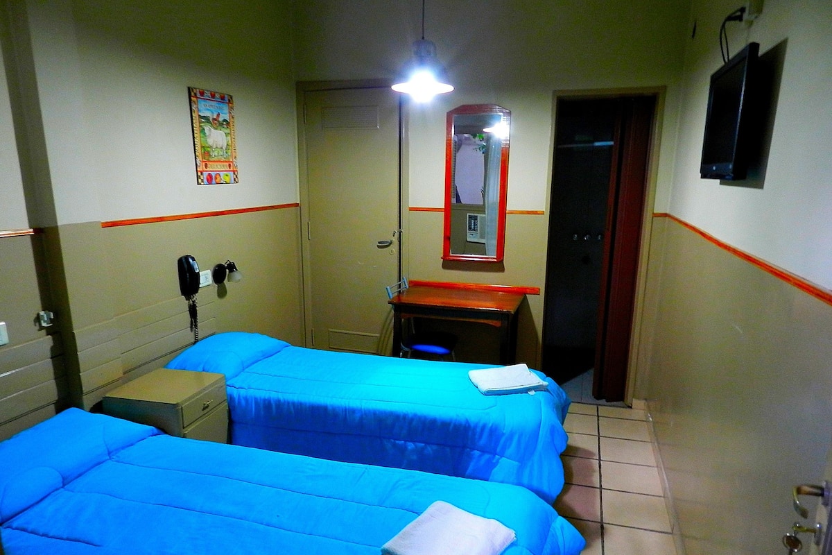 A hotel room with two beds, a desk, a telephone, and a mirror.