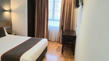 Una habitación de hotel con una cama, un escritorio y cortinas.