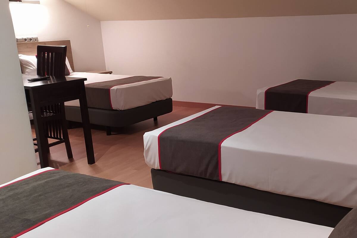 Hotellihuone, jossa on kaksi sänkyä, työpöytä ja tuoli.