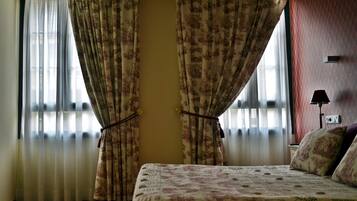 A room with a bed, curtains, and a lamp.