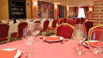 A banquet hall with tables set for dining, featuring red chairs and pink tablecloths.