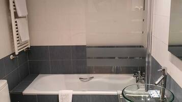 Une salle de bain moderne avec une baignoire, un lavabo en verre et des toilettes.