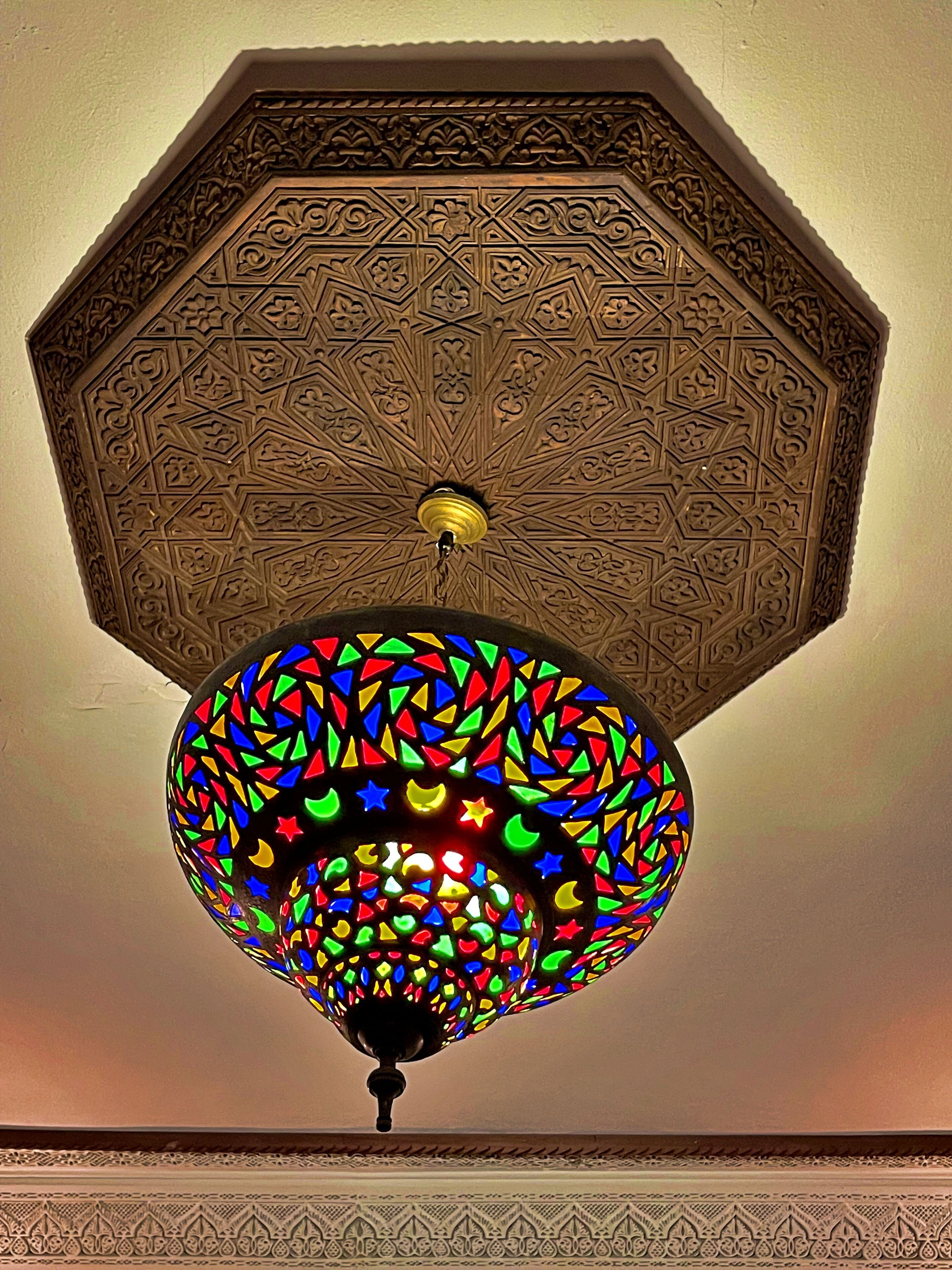 Un techo con intrincados diseños geométricos y una lámpara colgante de vitral.