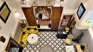 Amplia sala de estar con piso estampado, un conjunto de sofás, una mesa de centro y un tapiz decorativo.