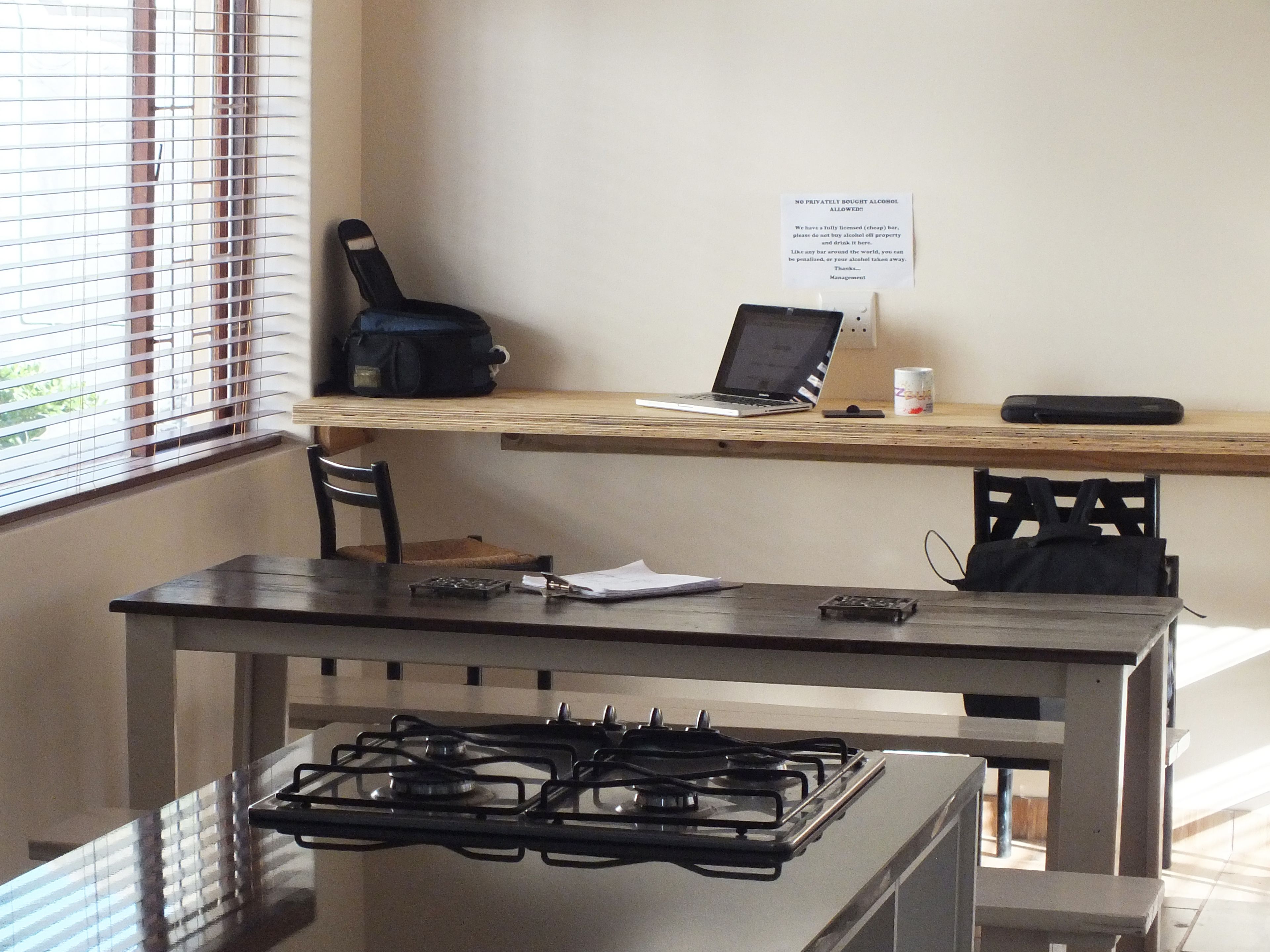 Una cocina con estufa a gas, una computadora portátil sobre una mesa de madera y una silla.