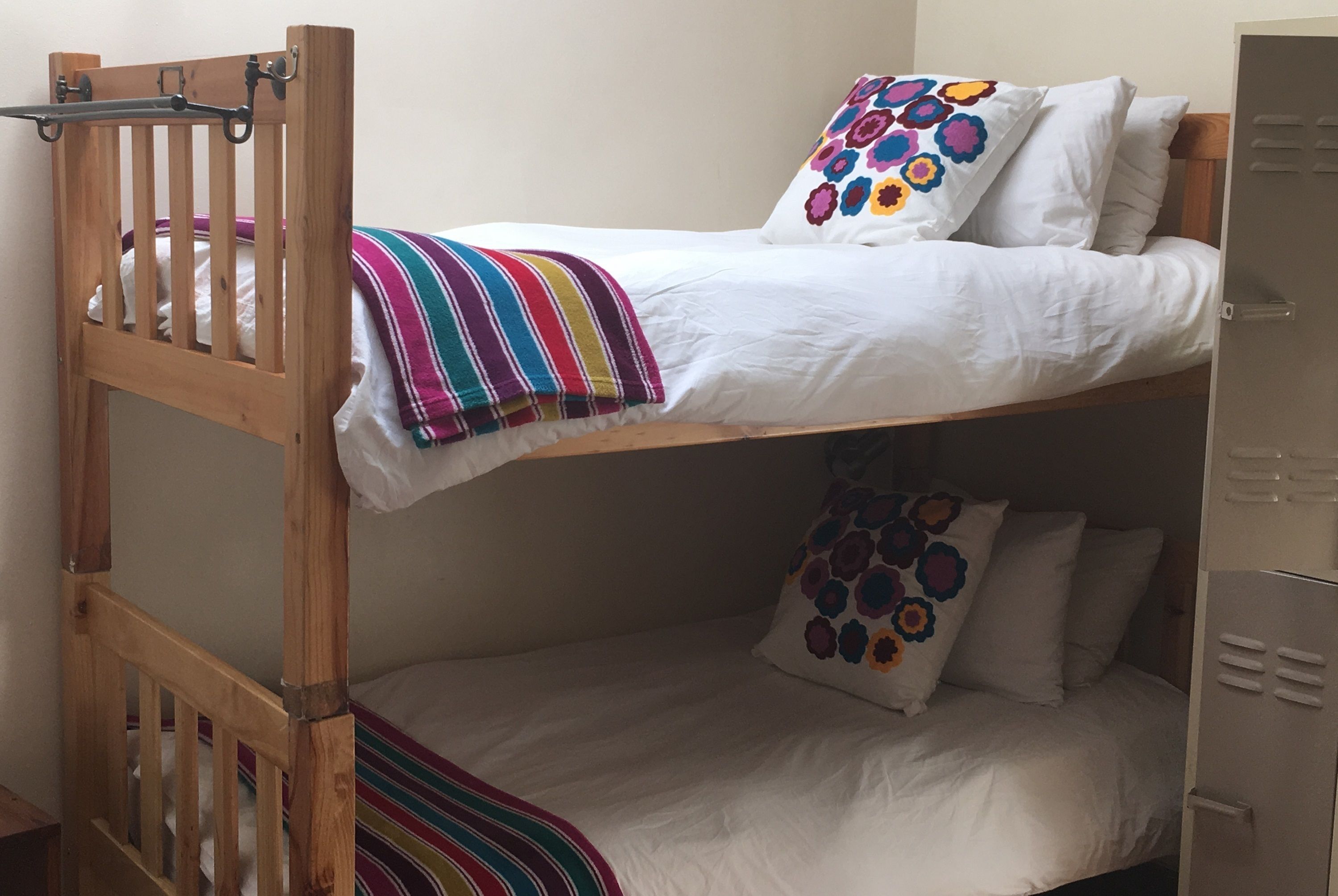 A bunk bed with a wooden frame, white bedding, and colorful pillows.