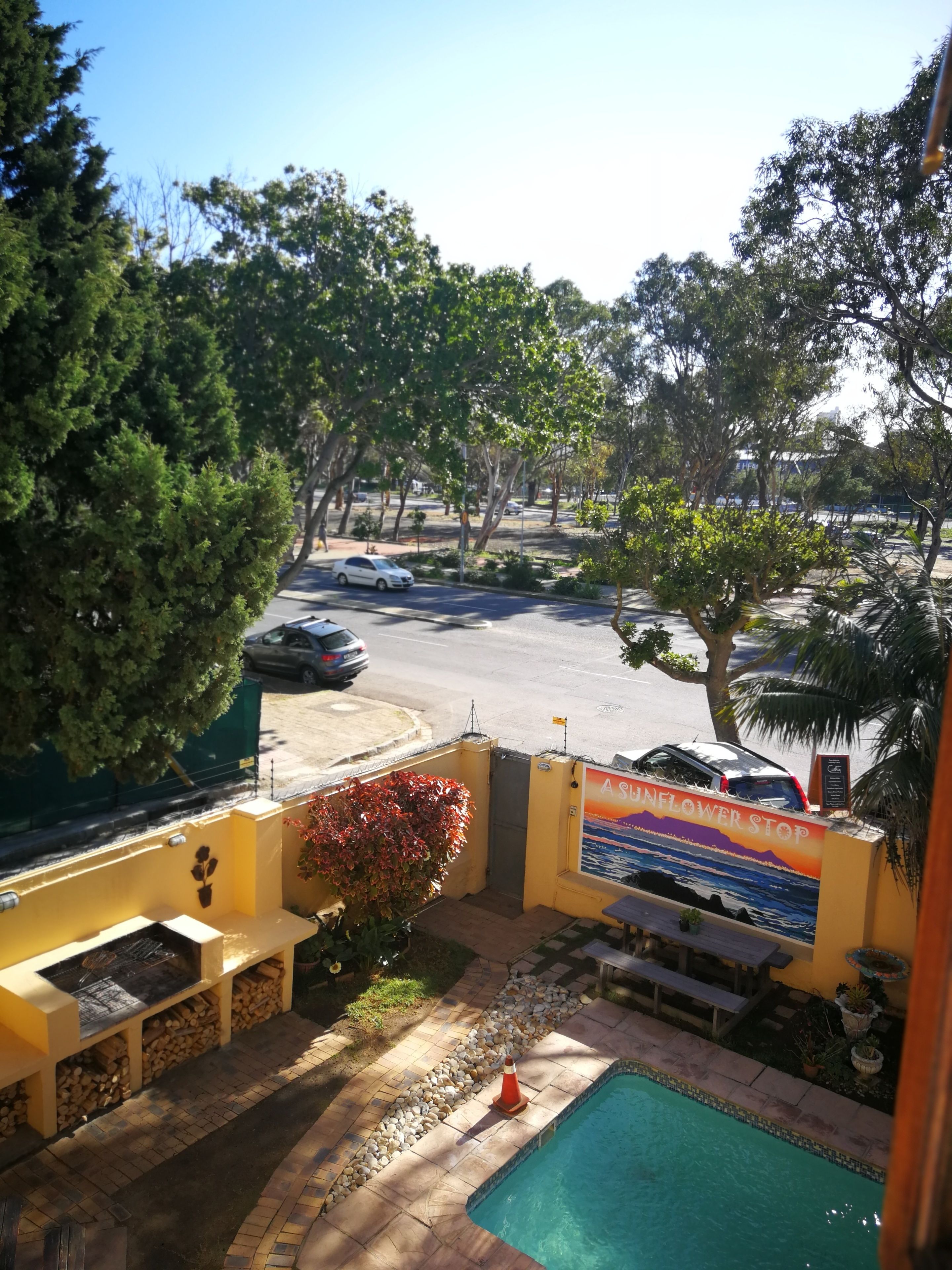 A pool area with a view of a parking lot and trees.