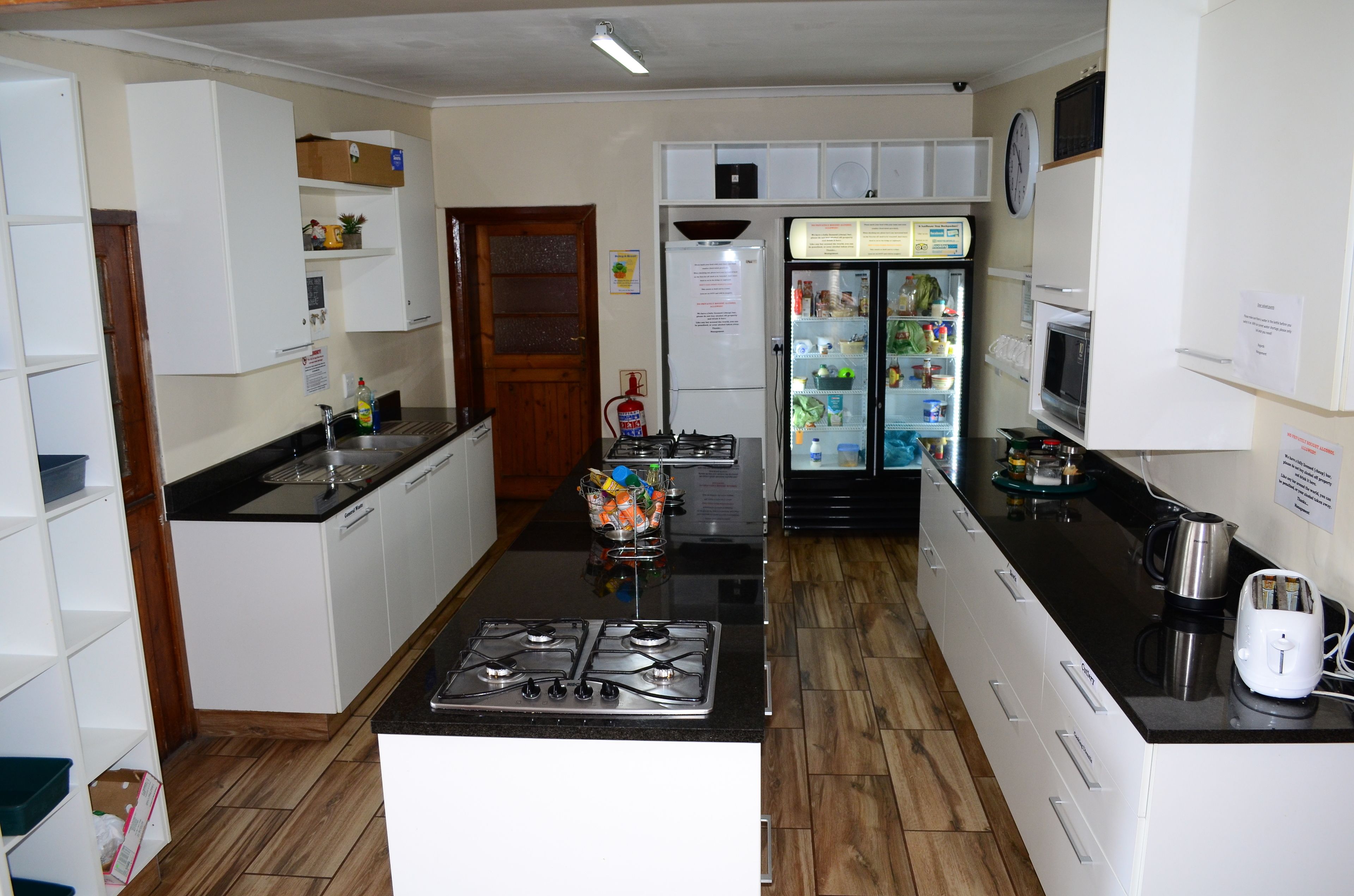 A compact kitchen with white cabinets, a gas stove, a refrigerator, and a microwave.