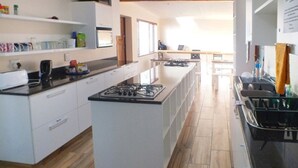 A modern kitchen with white cabinetry, a central island, and a black countertop. - A Sunflower Stop - Hostel (Cape Town)