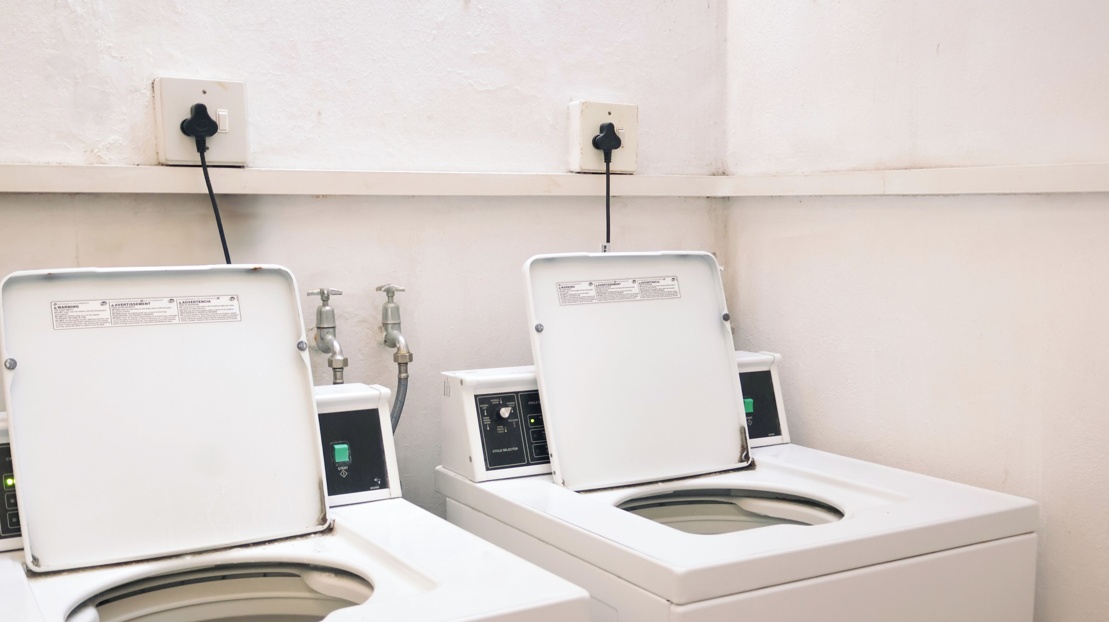 A public restroom with two toilets, each equipped with a control panel and a water outlet.