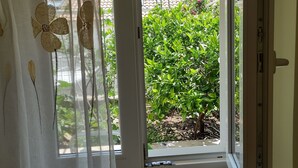 A room with a sliding glass door leading to a balcony with greenery. - Anna Guesthouse (Dubrovnik)