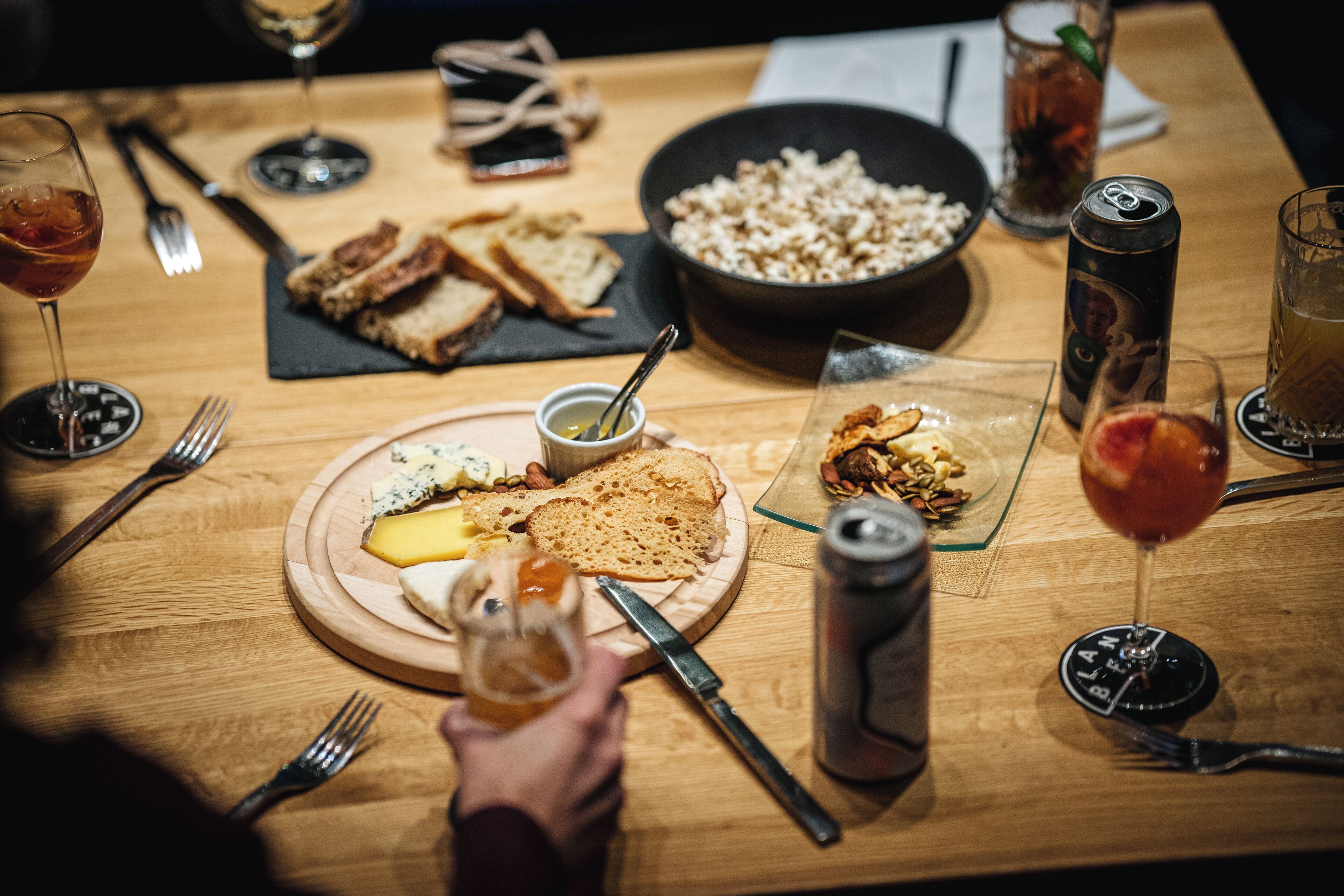 Uma mesa de madeira com diversos alimentos, utensílios e bebidas.