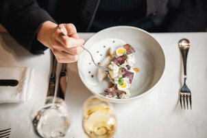 Une table à manger avec une assiette de nourriture, une fourchette, une cuillère et un verre à vin.