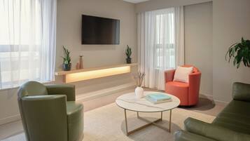 Una sala de estar moderna con un sofá, sillones, una mesa de centro y un televisor montado en la pared.