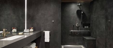 Un baño moderno con una decoración oscura, que incluye un lavamanos grande, una ducha y un perchero para toallas.