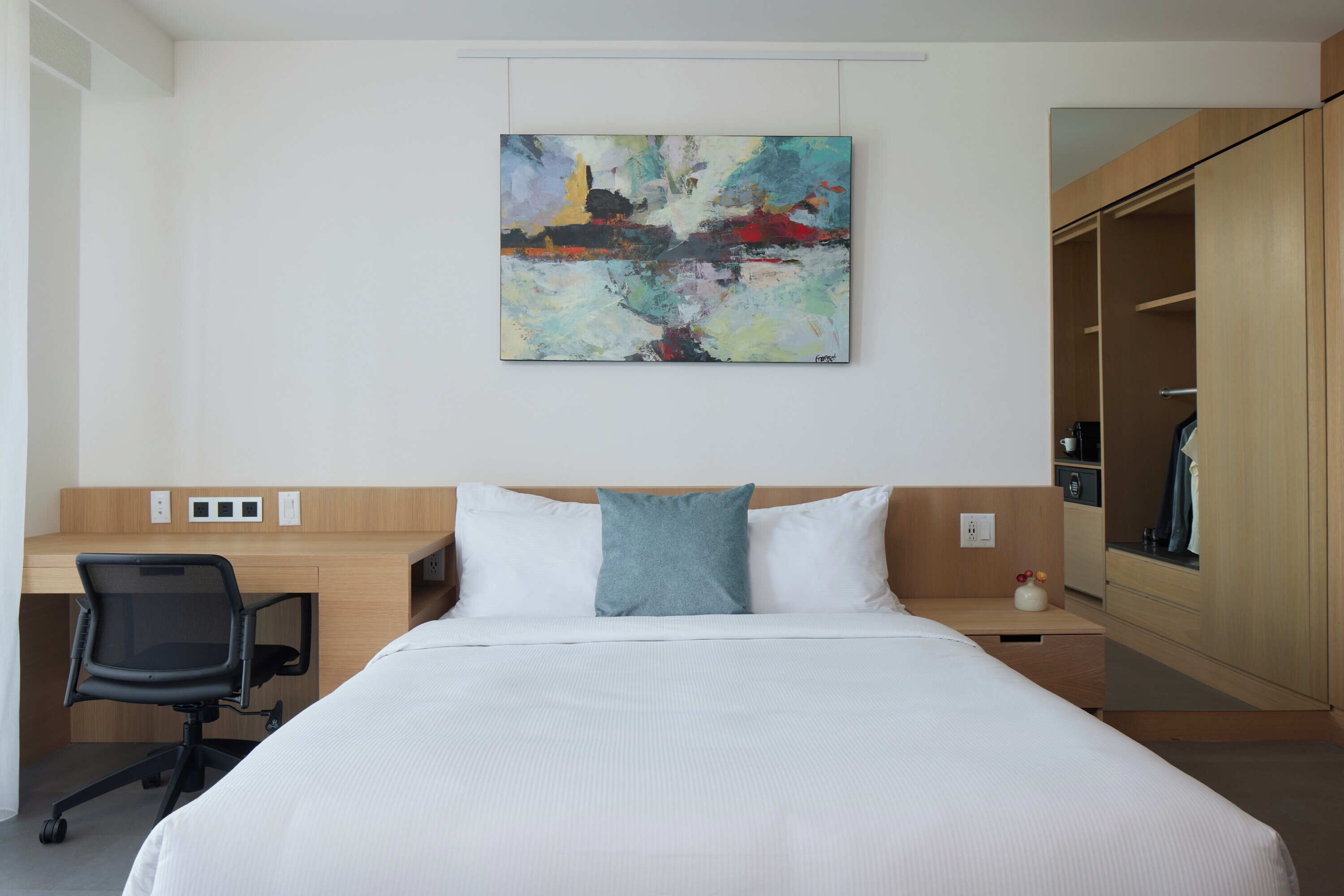 Una habitación de hotel con cama, escritorio y armario.