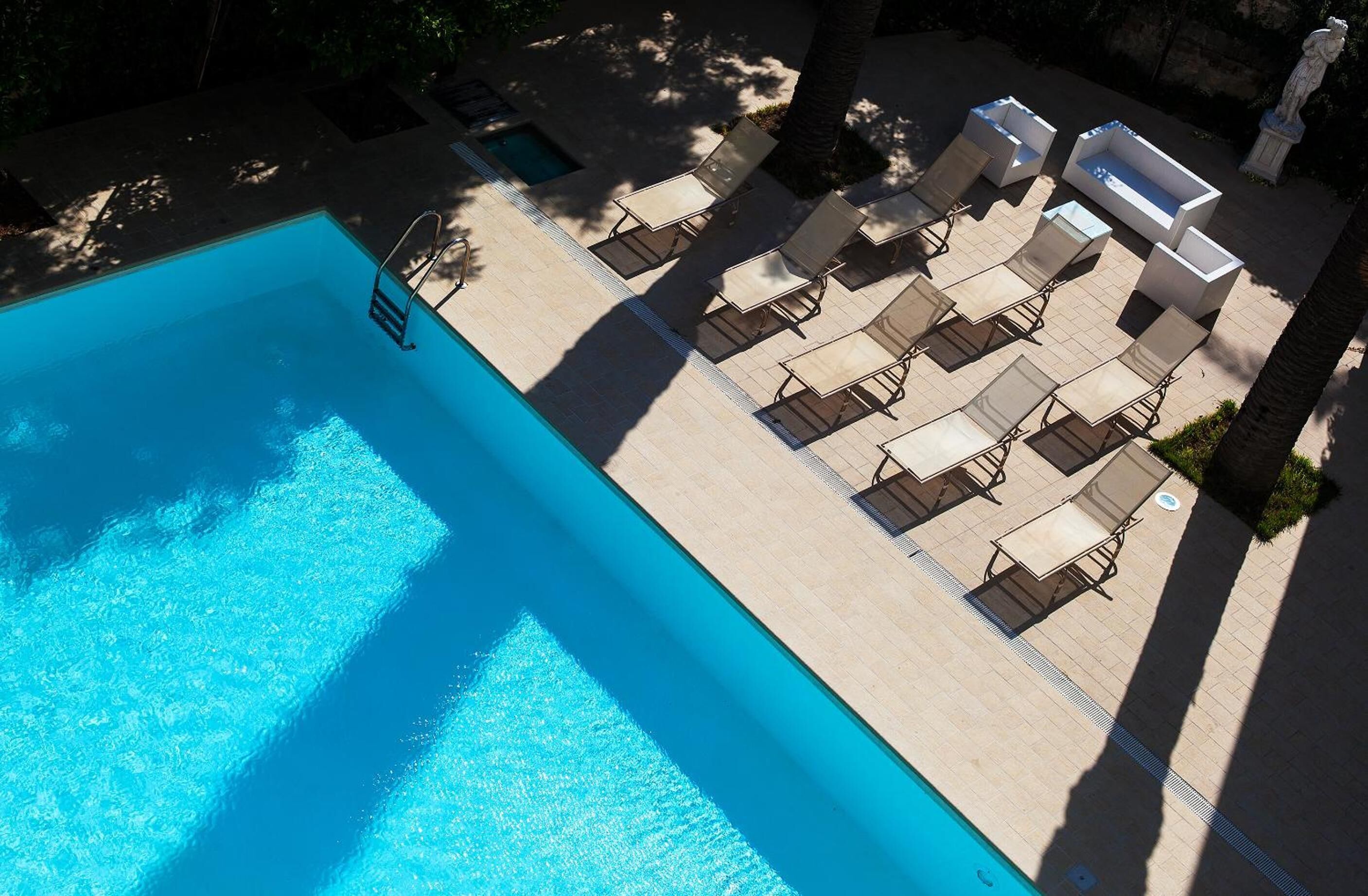 A swimming pool with lounge chairs and a statue in the background.