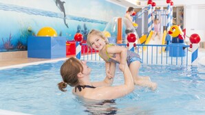 Una piscina interna con un murale raffigurante un delfino, un'area giochi e uno scivolo.