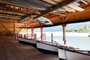 A covered boat dock with wooden beams and a view of a calm lake. - Familotel Kaiserhof (Berwang)